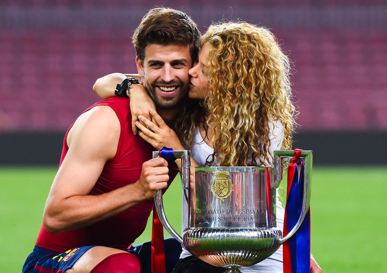 Shakira kissing Gerard Piqué on the cheek while posing with the Copa del Rey trophy in 2015