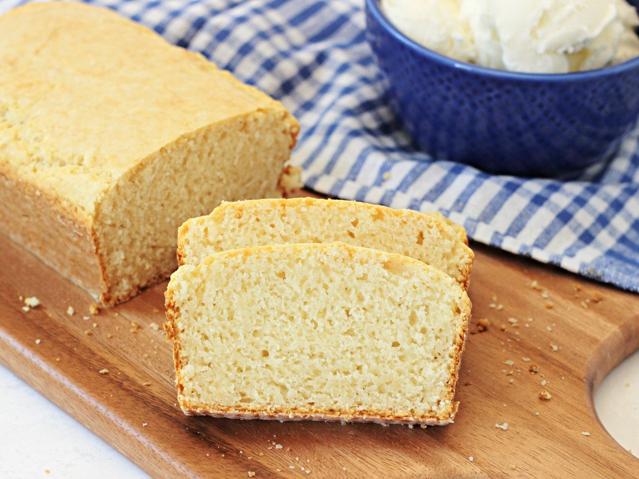 Sliced bread loaf with ice cream in a blue bowl on a wooden board