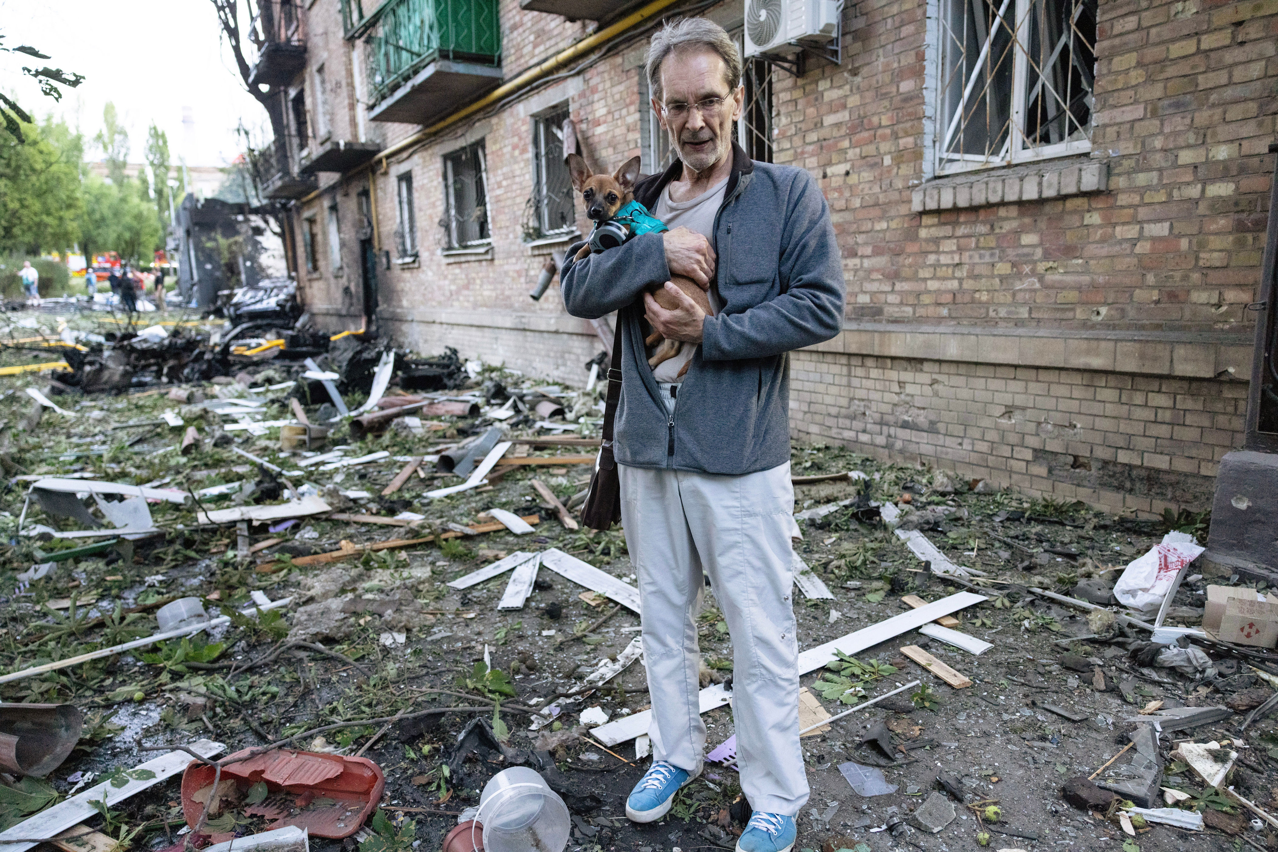 A Ukrainian man holds his dog looking at the damage to this apartment building (Getty)