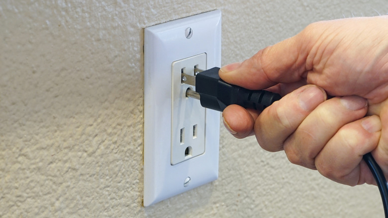 Person plugging cord into outlet
