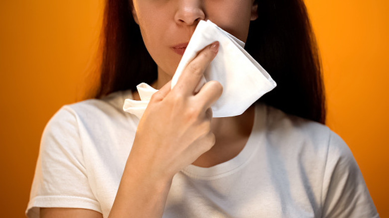 Girl wiping face with napkin in front of orange background
