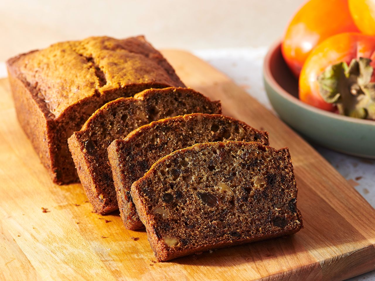 Sliced persimmon bread on a wood cutting board.