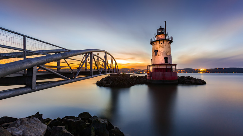 Historic Sleepy Hollow Lighthouse at dusk with silhouetted bridge and glassy water