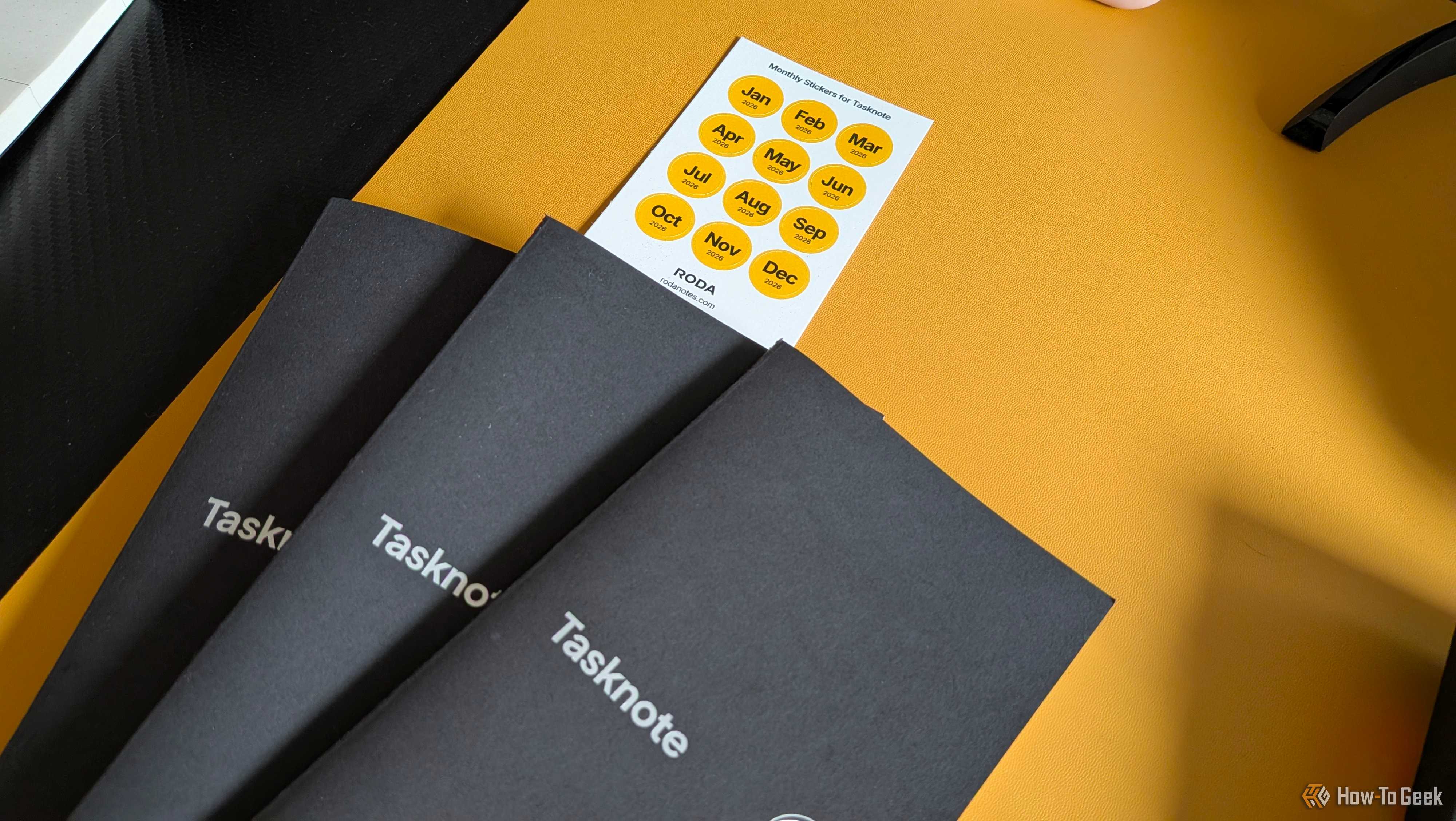 Three Tasknote notebooks fanned out next to a Roda monthly sticker sheet for 2026.
