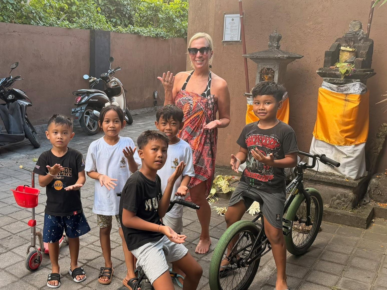 A foreigner in a courtyard in Bali hanging out with Balinese kids.
