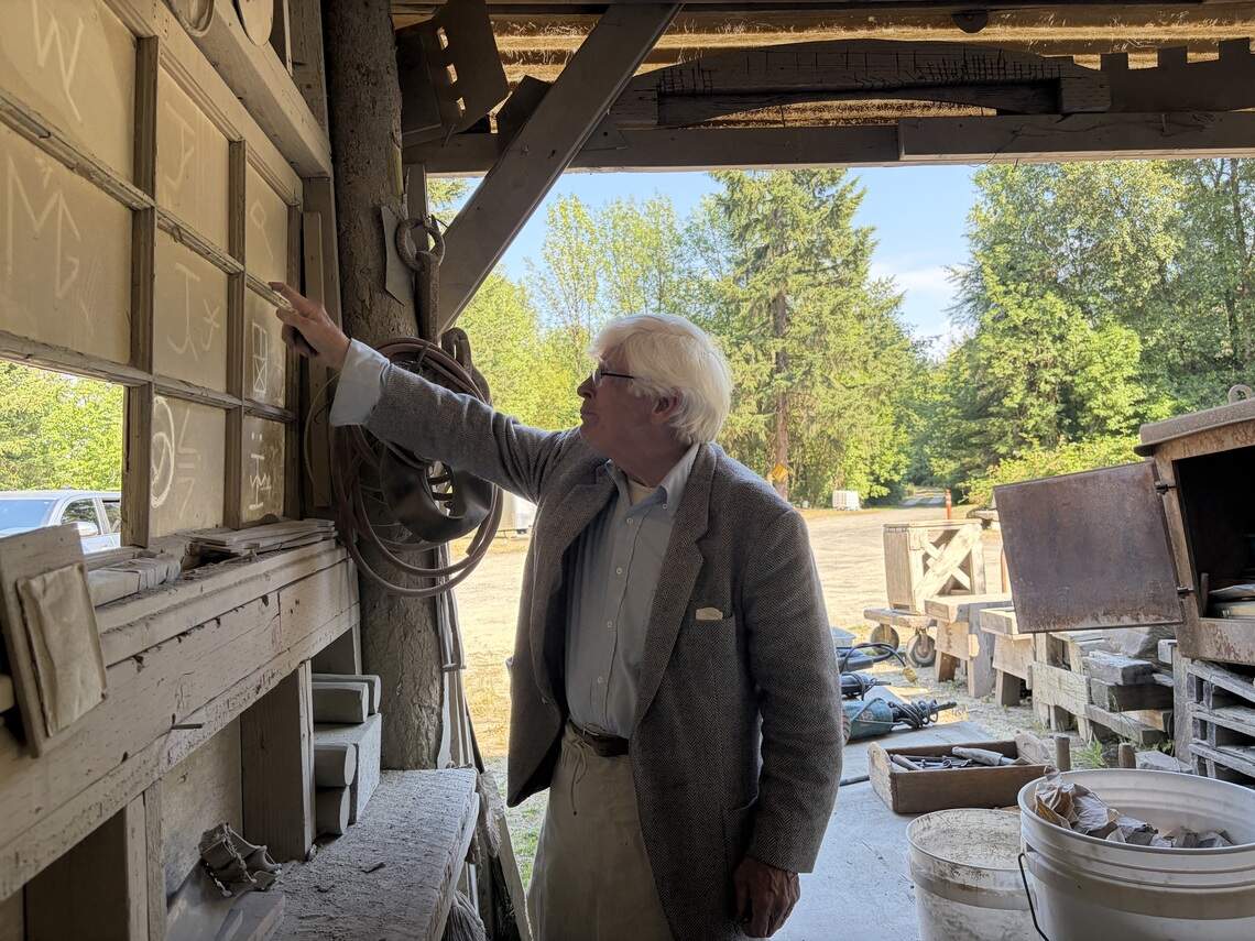 Master Stone Carver Keith Phillips points out local stonemason symbols used to mark work. The symbols have been carved in a window in Phillips’ workshop, at the base of Hercules #1 Quarry in Tenino, WA.