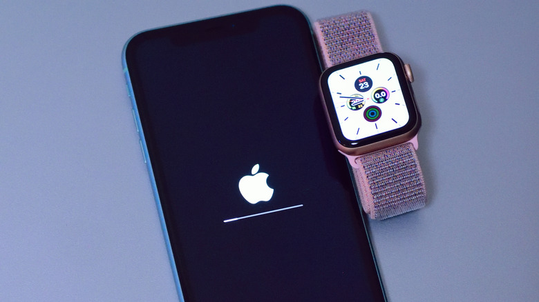 Update being installed on an iPhone placed alongside an Apple Watch on a light surface