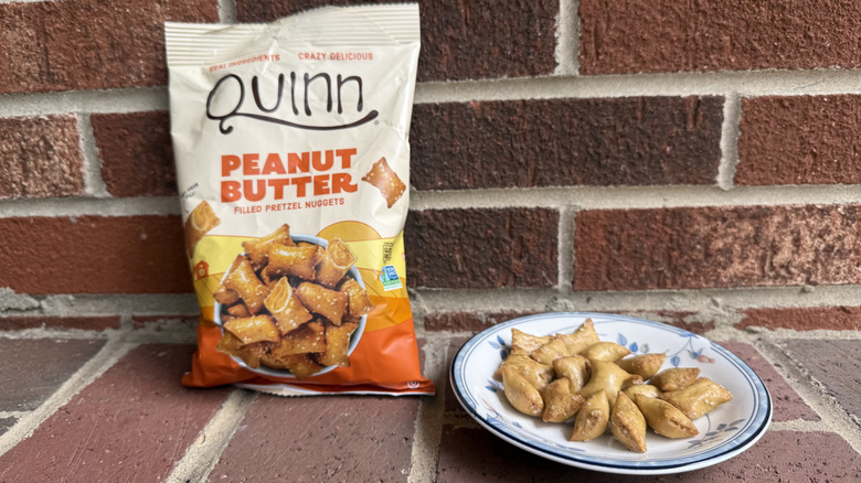Bag of Quinn peanut butter-filled pretzels on brick surface, with some displayed on adjacent plate