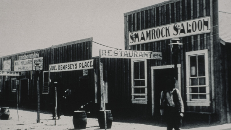 A cowboy stands outside an Old West saloon
