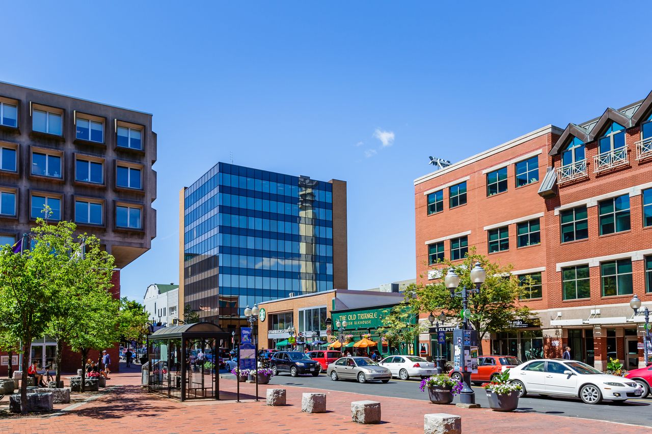 City street with modern and historic buildings parked cars and trees