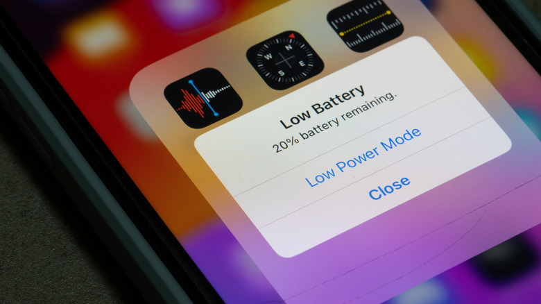 Low battery warning on an iPhone with utilities app group open in the background