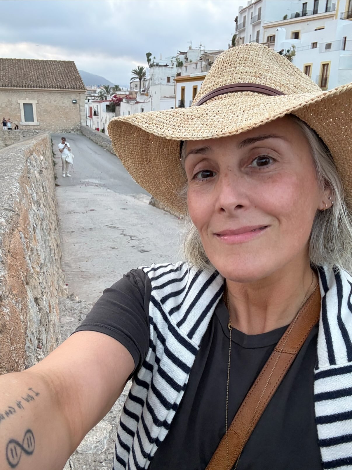 A selfie of Ricki Lake in a straw hat and striped vest, smiling slightly.
