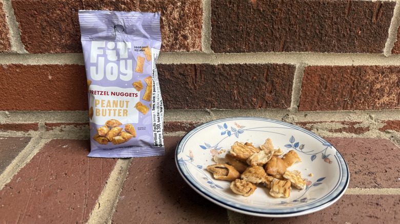 Small pouch of FitJoy peanut butter-filled pretzels on brick surface, with some displayed on adjacent plate