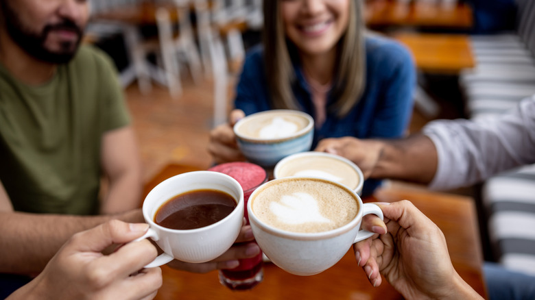 Several people holding cups of coffee at a cafe