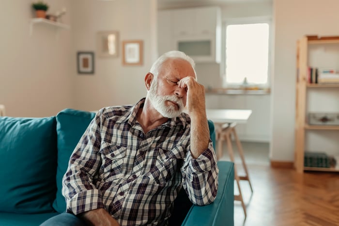 A person sitting on a couch holding their face.