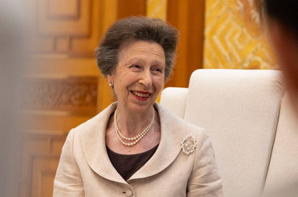 Princess Anne in a cream jacket and red lipstick smiling