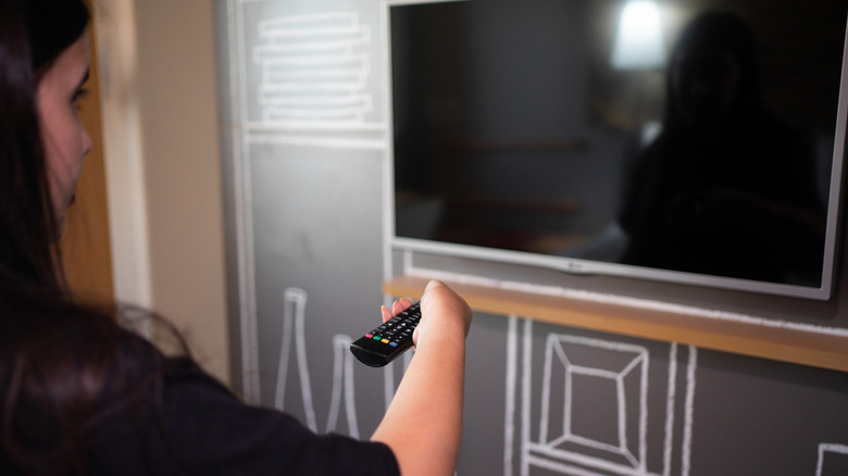 A woman shutting off a smart TV.