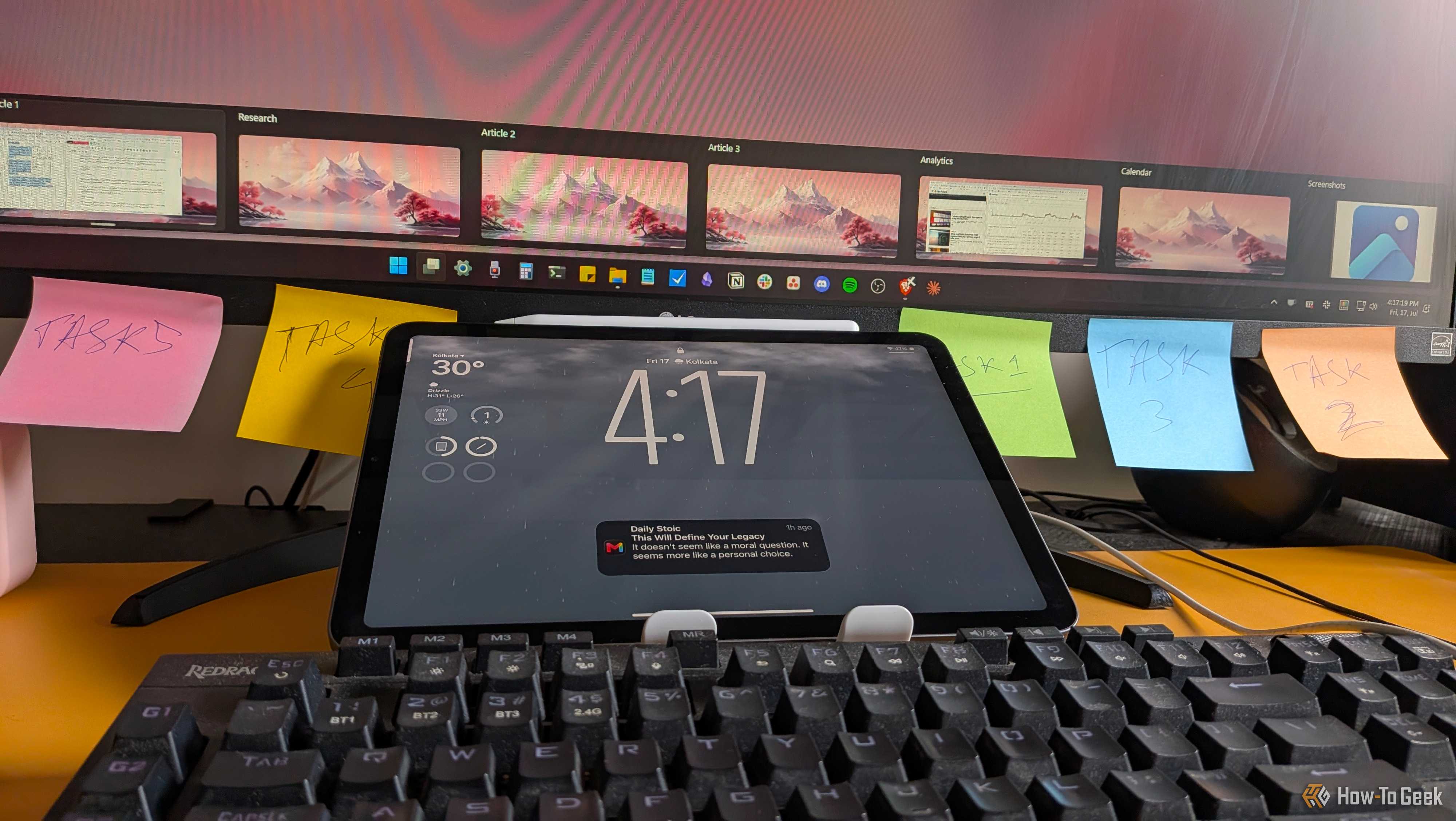 iPad lock screen showing 417 time propped against a monitor lined with five colored task sticky notes.