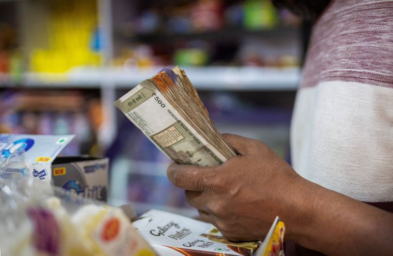 A man holds Indian currency notes inside a shop in New Delhi