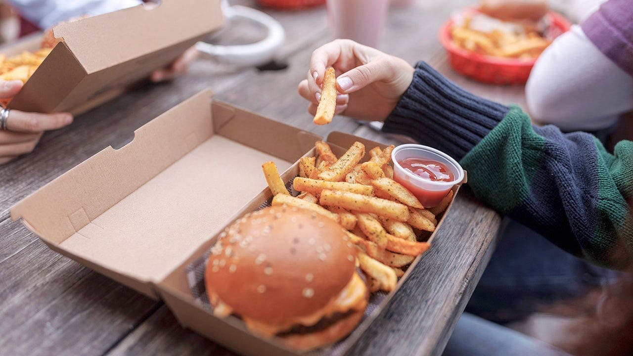 A person eats a burger with fries.