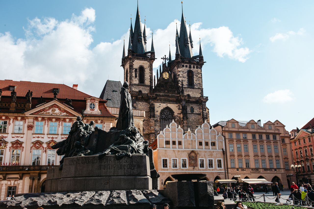 View of a historical square with a statue ornate buildings and a church with tall spires