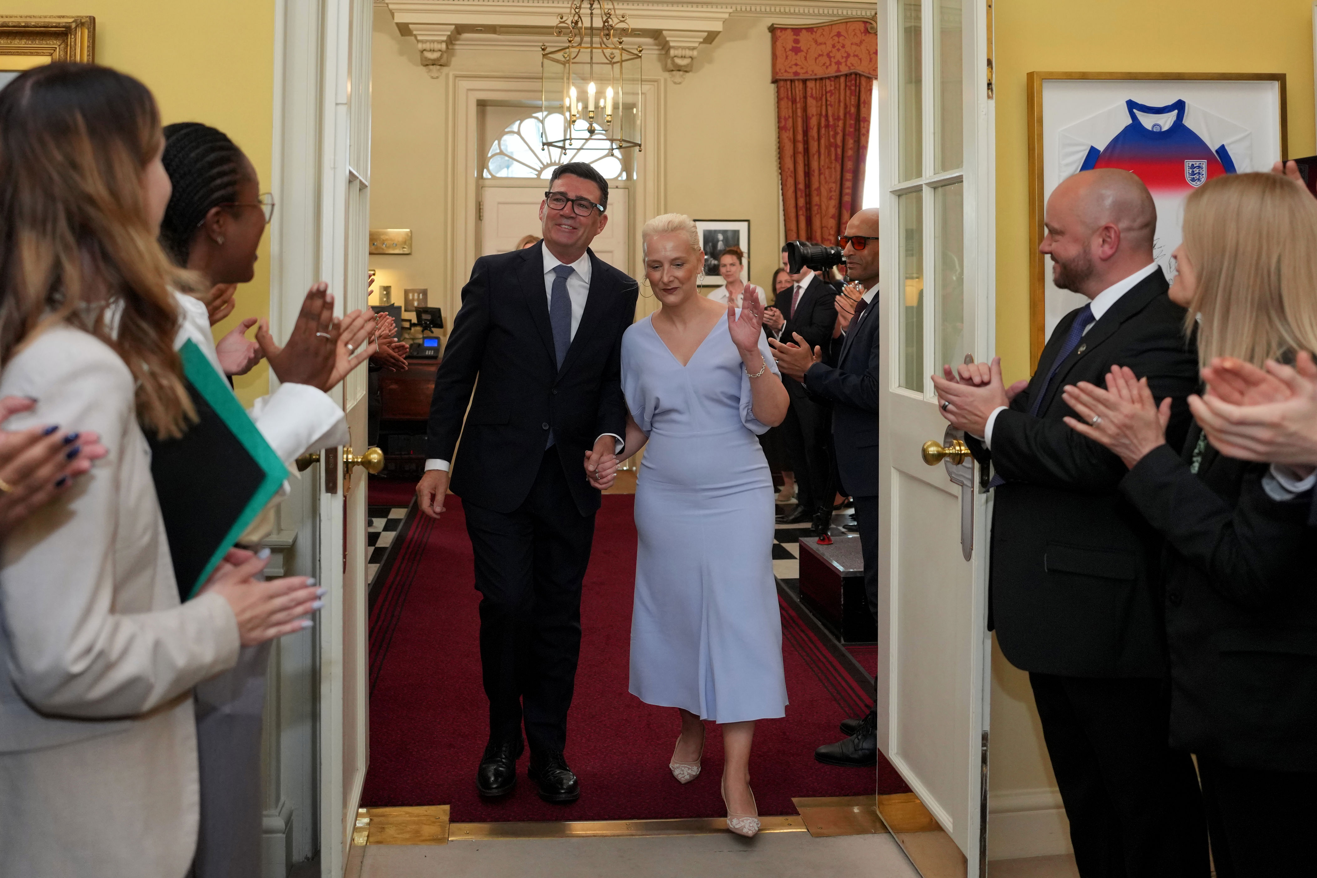 New British Prime Minister Andy Burnham and his wife Marie-France van Heel are welcomed by staff as they arrive inside 10 Downing Street (Getty)