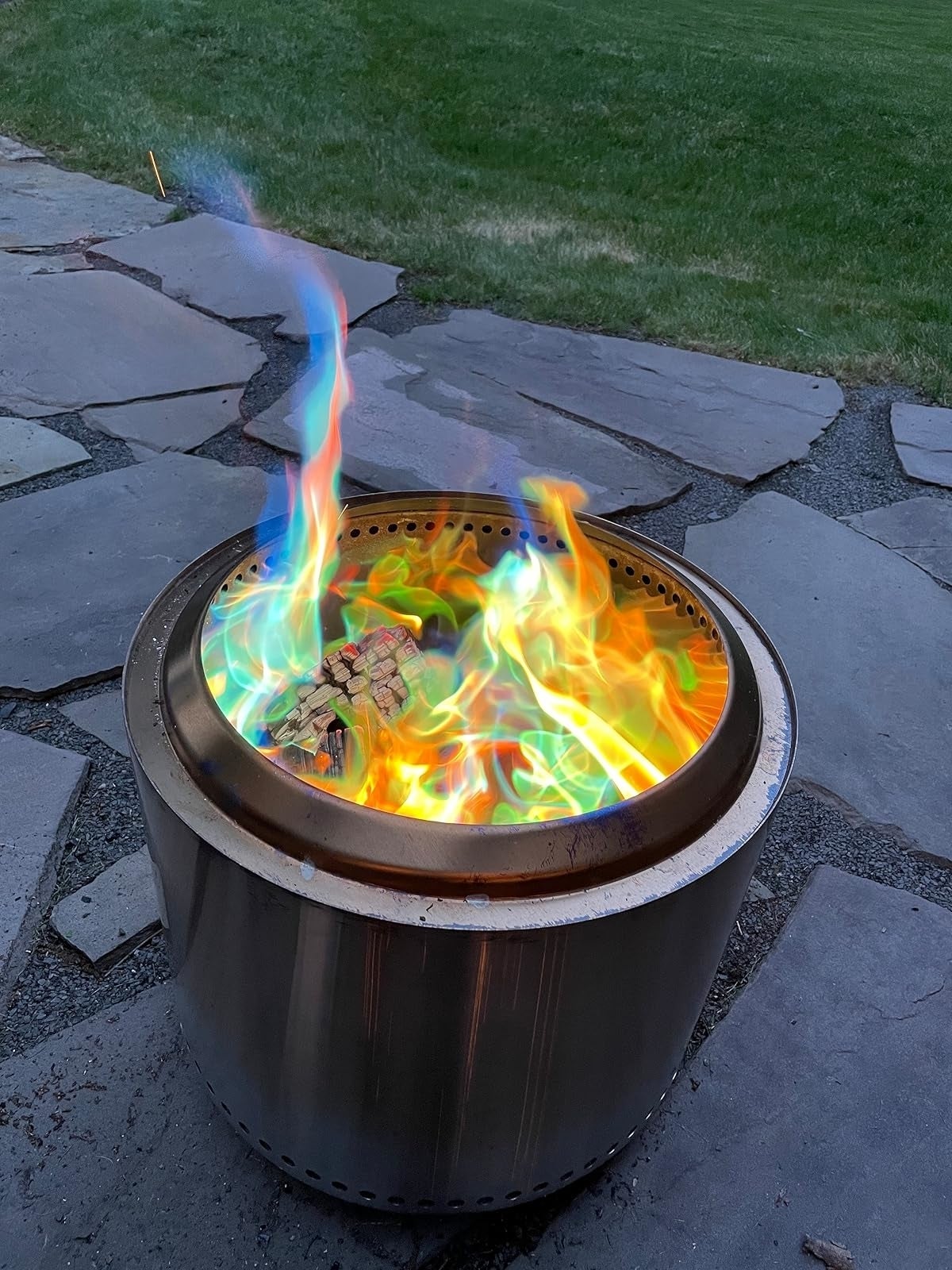 Portable fire pit on a stone patio, showcasing vibrant, multicolored flames