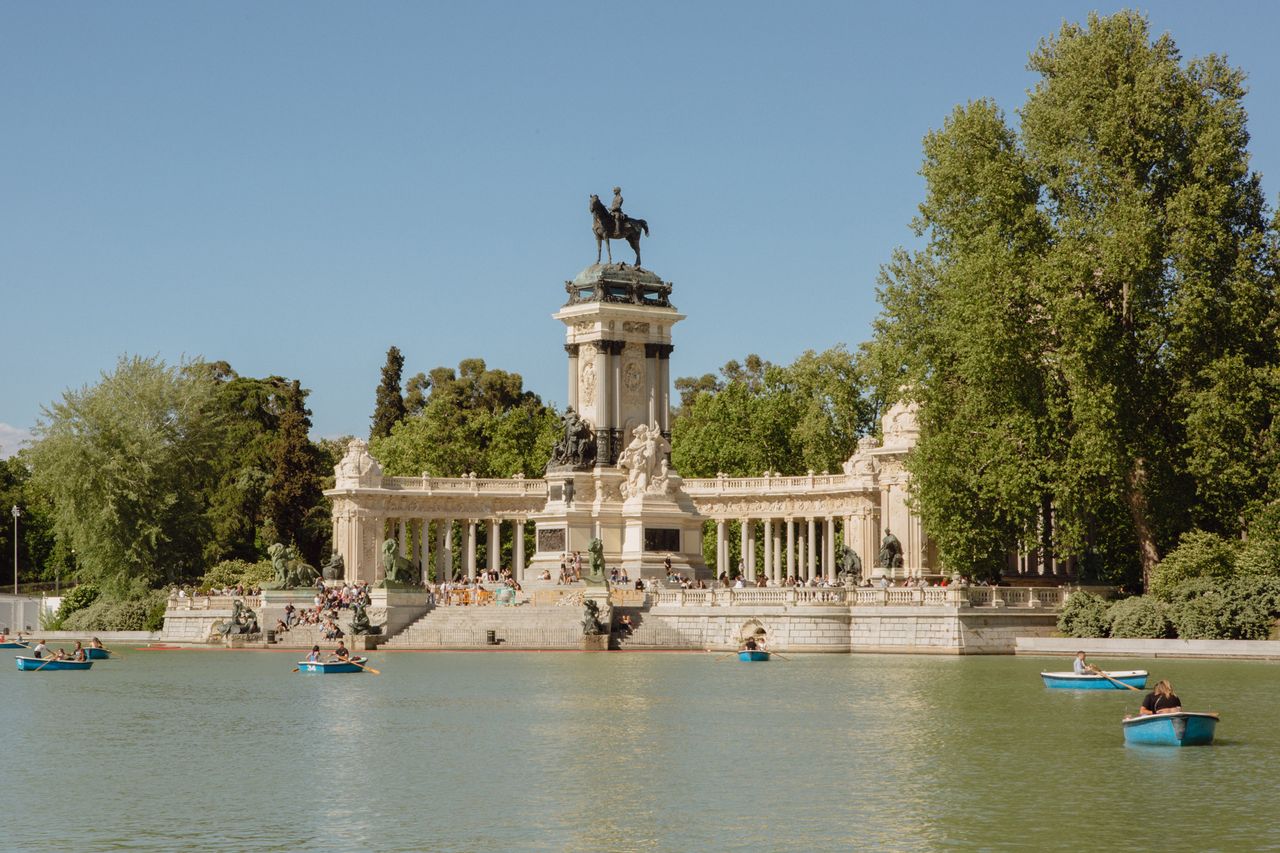 Outdoor scene with a monument surrounded by water and people boating nearby