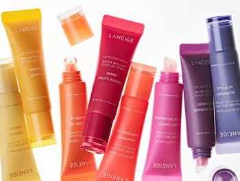 Various LANEIGE Lip Glowy Balm tubes labeled with flavors like Mango and Berry, highlighting shea and murumuru butters for lip nourishment