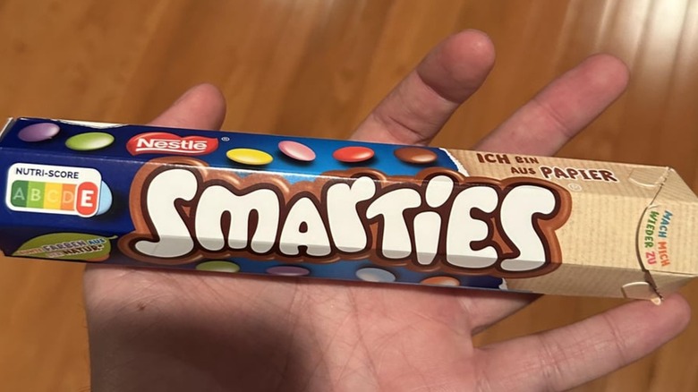 Hand holding a packet of Smarties Chocolate Candy