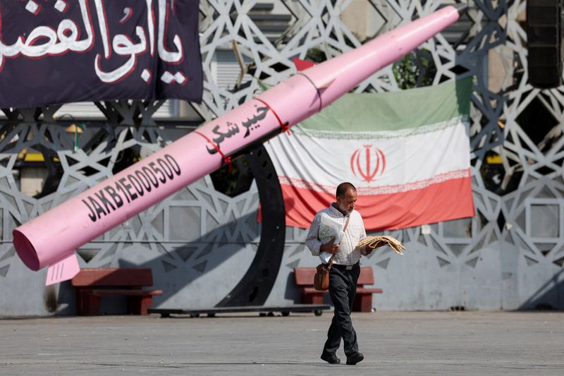 A man walks next to a symbolic mockup of an Iranian missile at Imam Hussein Square in Tehran