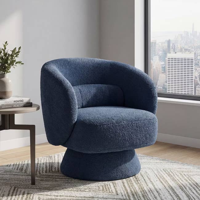 Plush swivel chair in textured fabric beside a table, with a cityscape view from the window