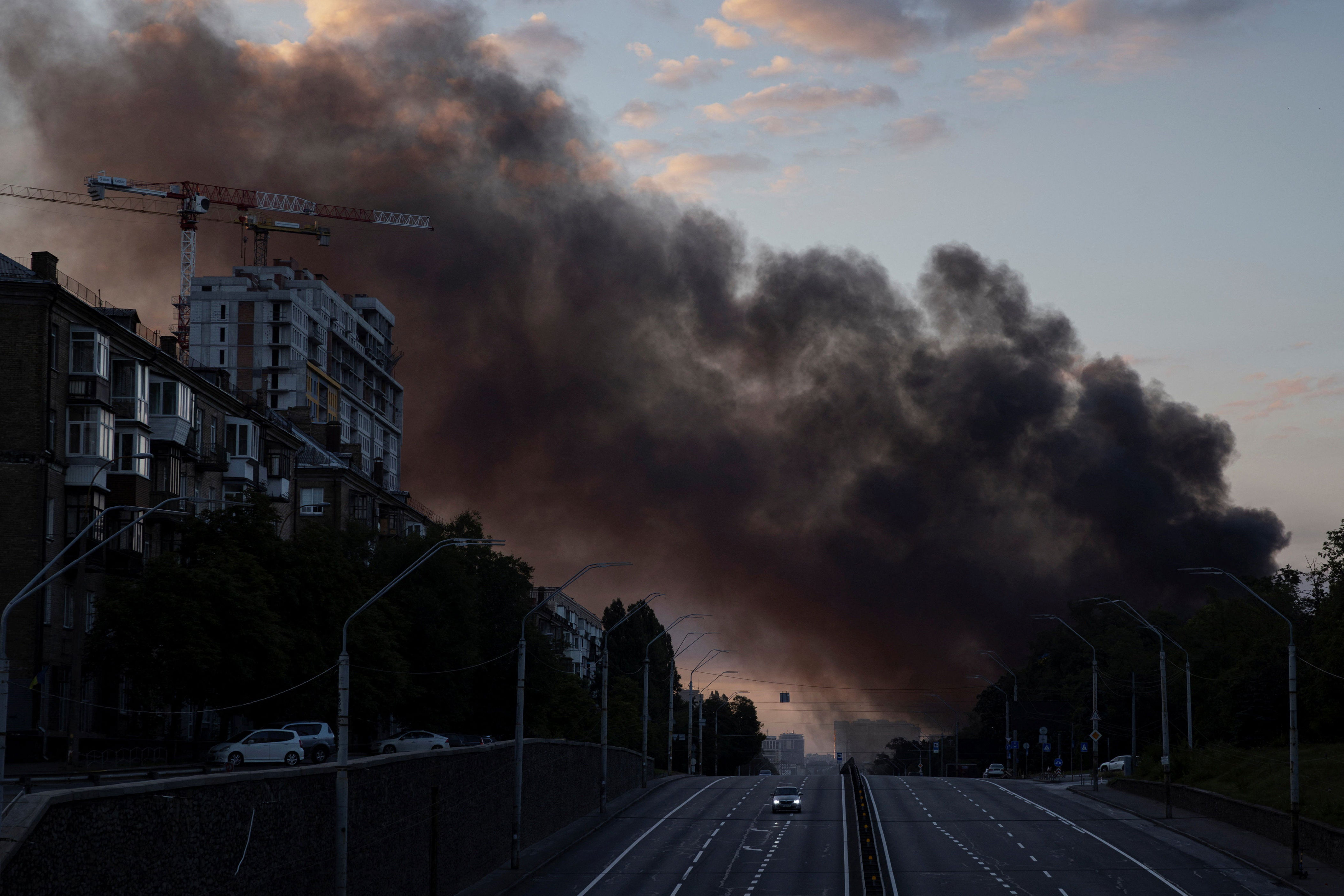 A column of smoke rises over the city as a car drives on a highway following Russian missile strikes, amid Russia’s attack on Ukraine, in Kyiv, Ukraine, July 19, 2026 (Reuters)