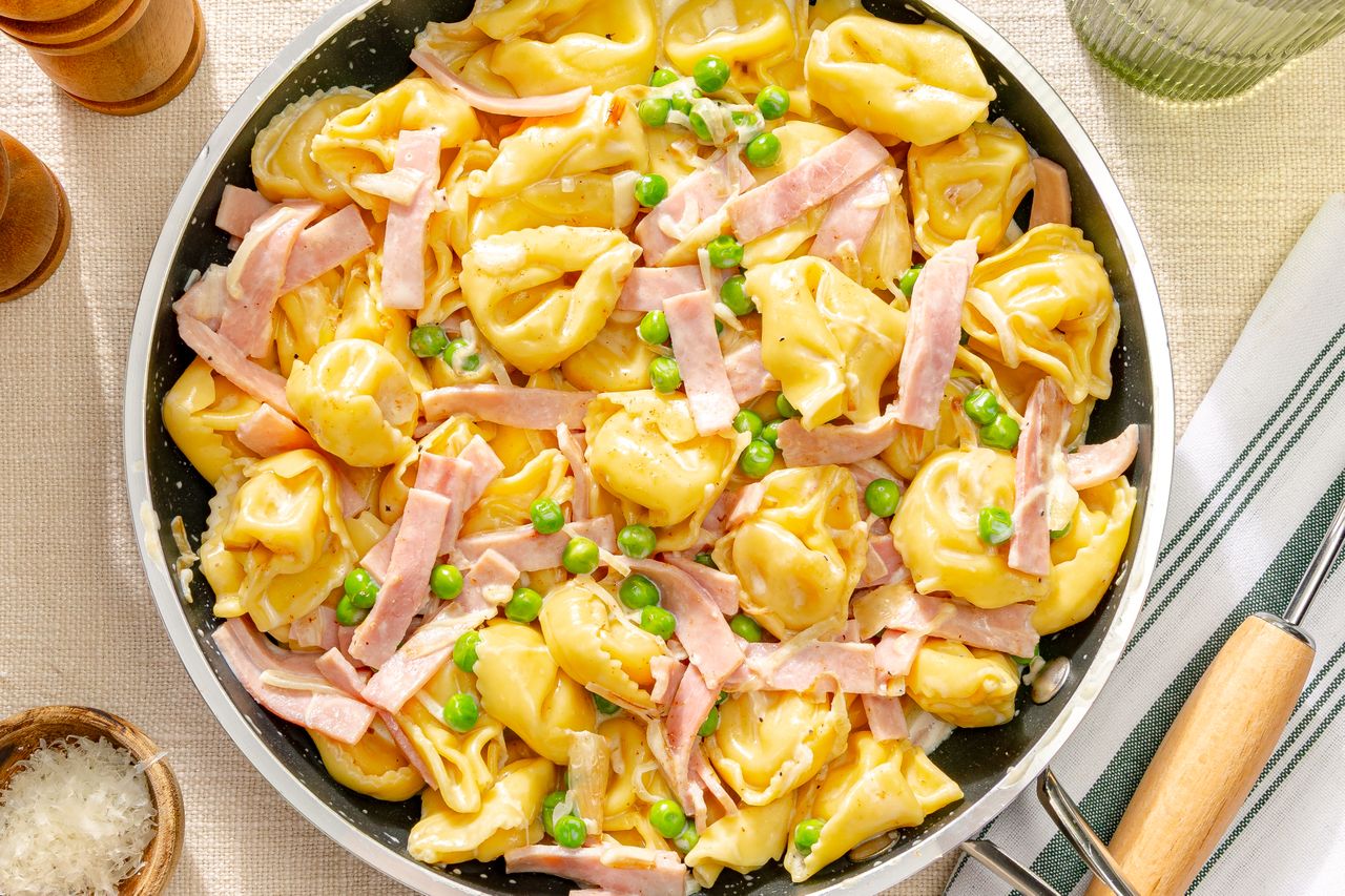 Creamy pasta with ham and peas in a skillet garnished and prepared for serving