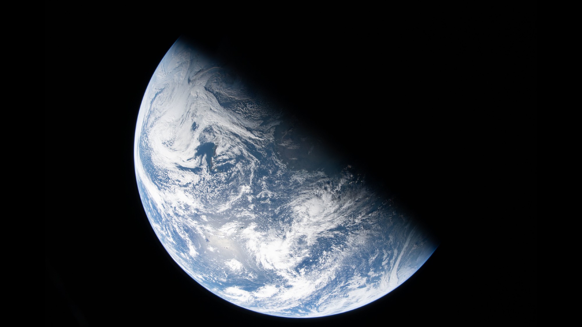 a photograph of earth from space, with half of the planet hidden by black shadow