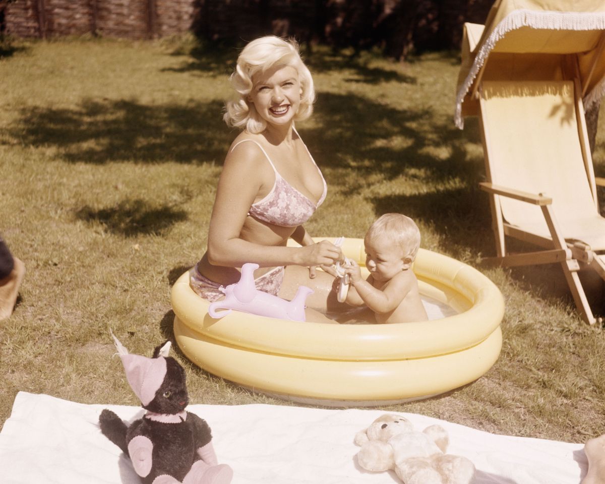 Jayne Mansfield in a yellow kiddie pool with her son in a garden setting