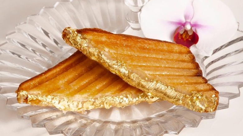 The Quintessential Grilled Cheese on a plate next to an orchid on a glass plate.