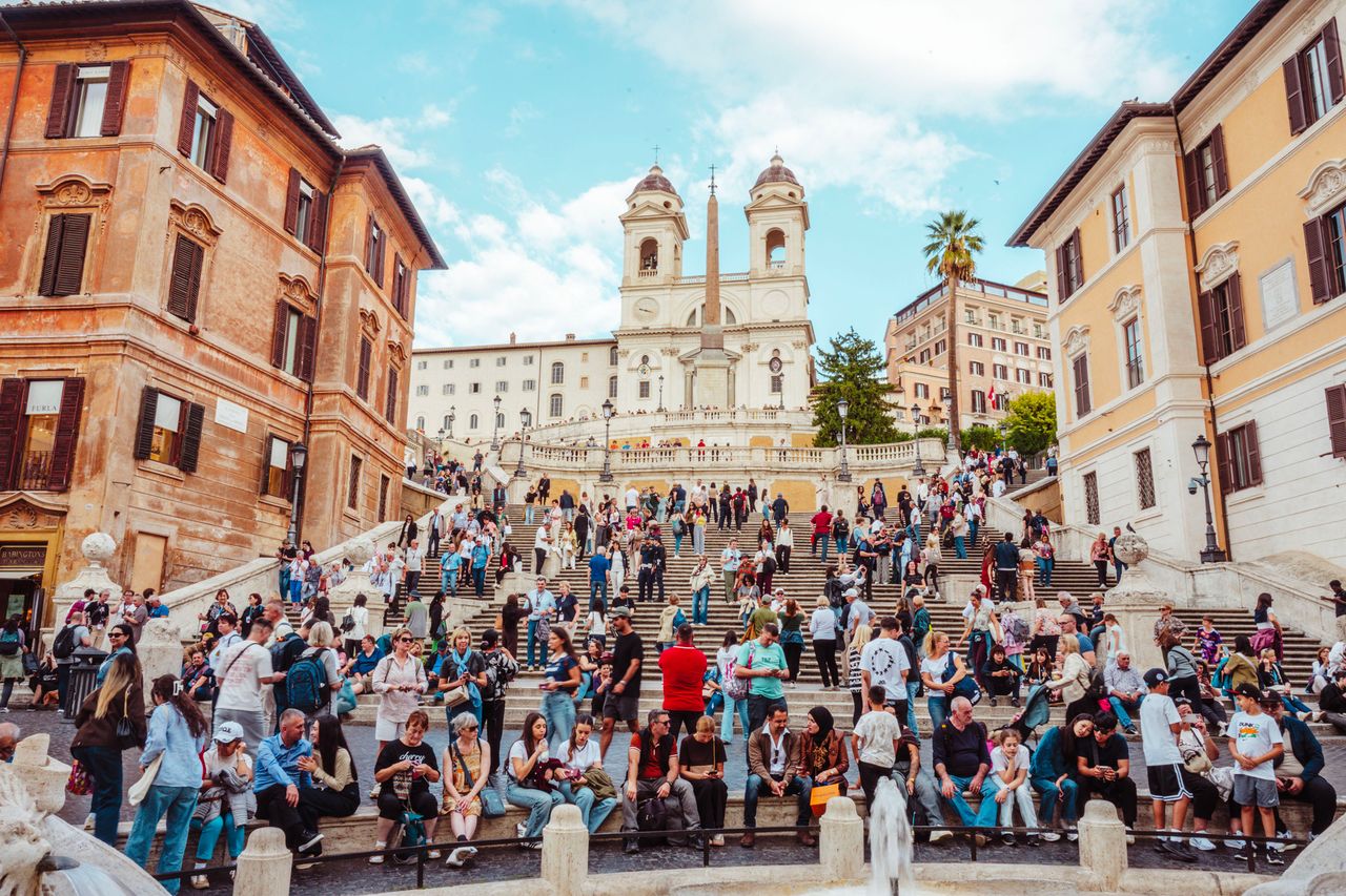 A large crowd on the Spanish Steps in Rome Italy with historical buildings and the Trinit dei Monti church in the background