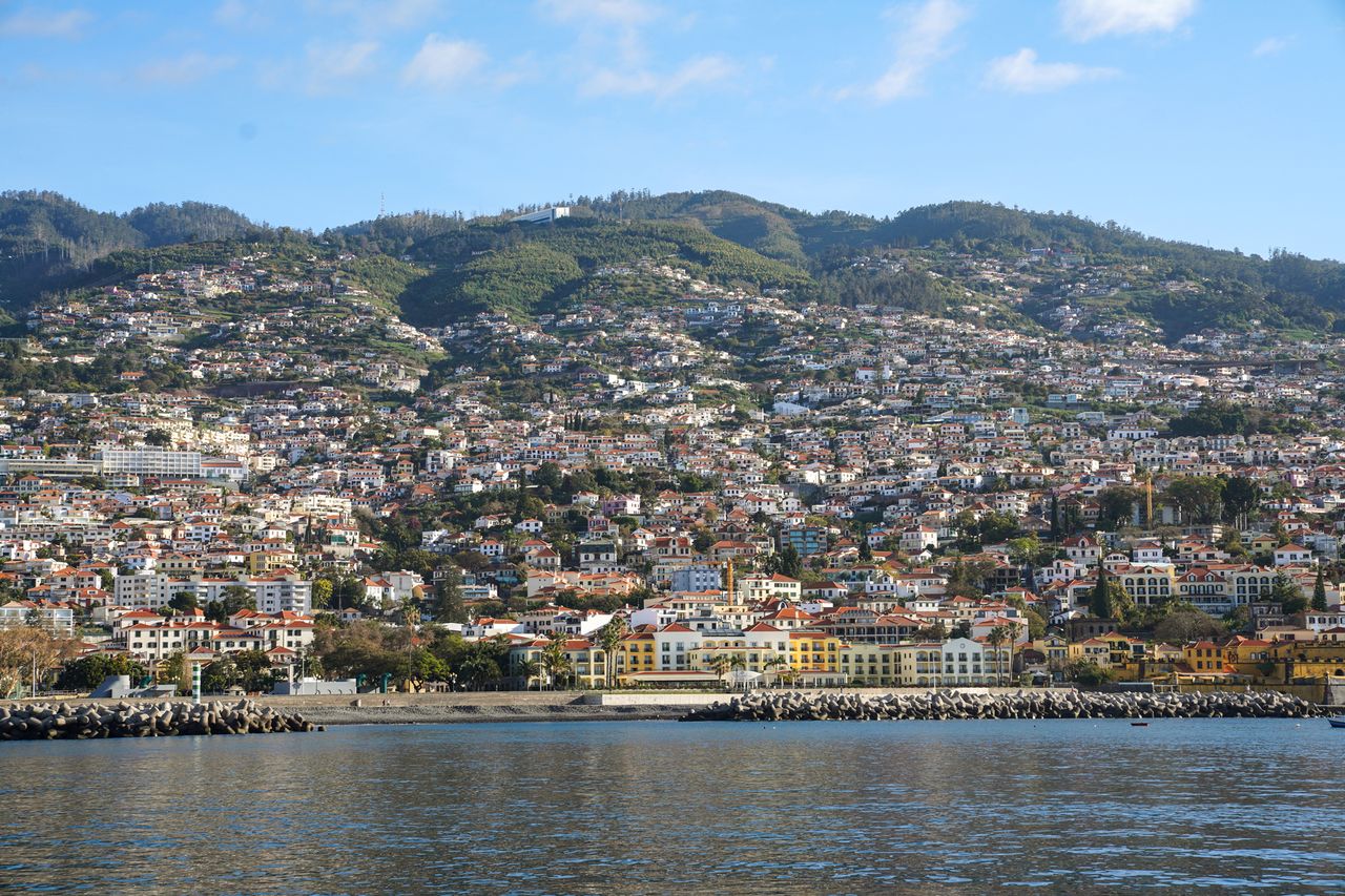 A coastal city with a view of hills and numerous buildings seen from the water