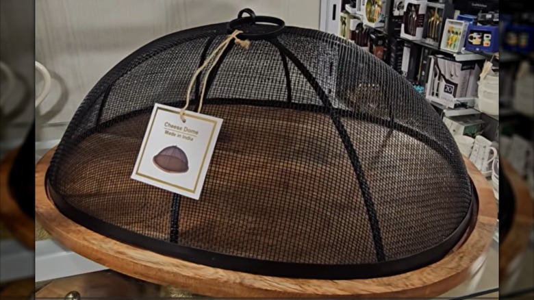 Wood platter with black screened food dome with tag at a HomeGoods store.