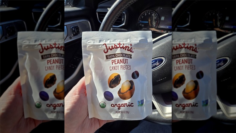 Hand holding a bag of Justin's Dark Chocolate Peanut Candy Pieces