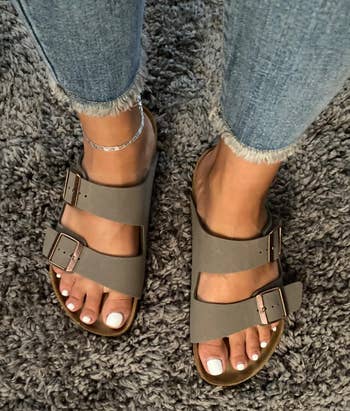 reviewer's feet wearing the dark gray sandals