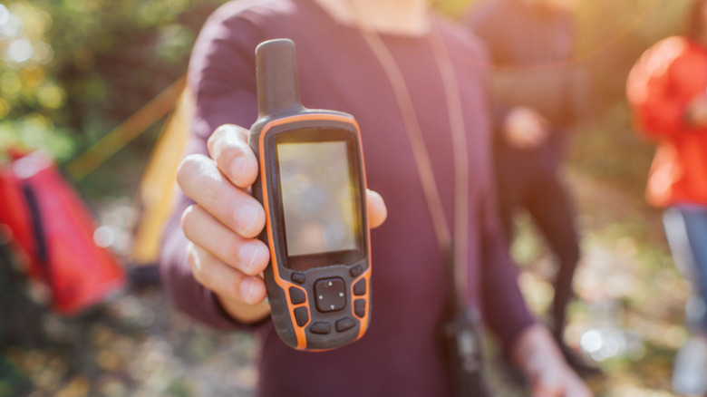 Person holds holding satellite phone up to camera in sunlight