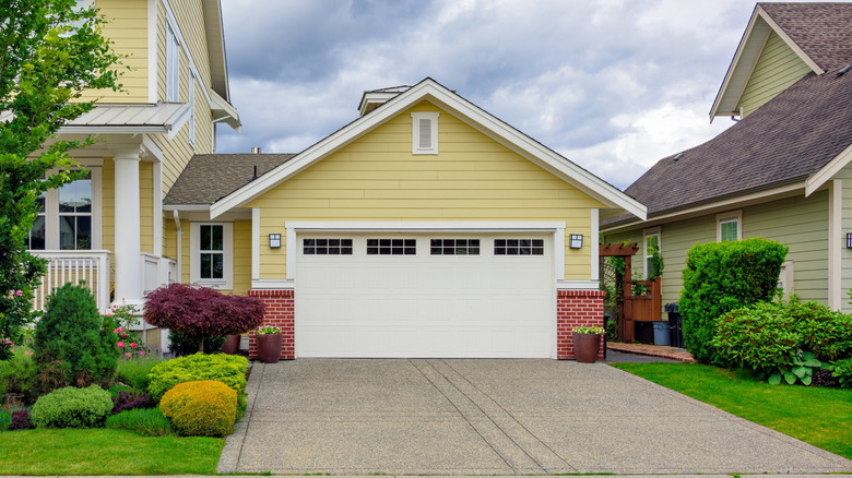 A yellow house with a concrete driveway leading up to it