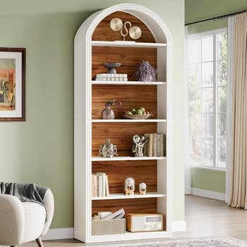 Elegant arched bookshelf with decorative items, vases, and books, situated in a comfortable, modern living room setting