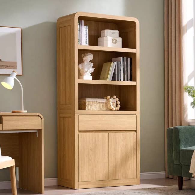 Wooden bookshelf with books and decor items, next to a lamp-lit desk. Cozy and functional home office setup