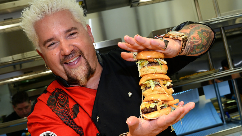 Guy Fieri holding a stack of hamburgers