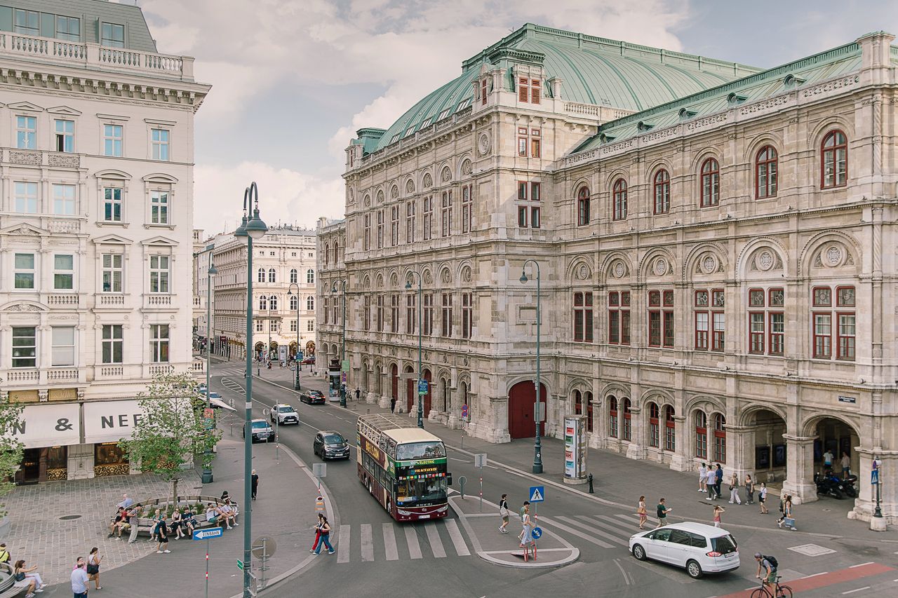 A street scene with a large ornate building pedestrians and a bus in Vienna