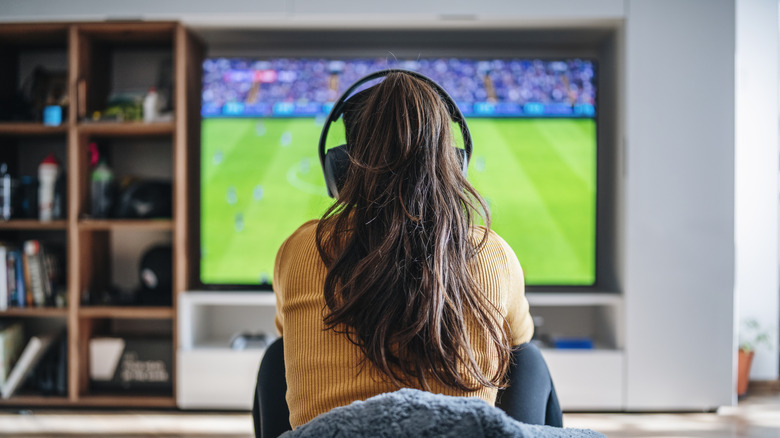 A woman wearing a gaming handset while gaming on a TV.