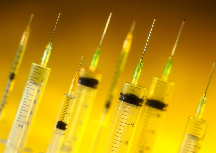 A bunch of syringes are shown against a yellow backlight.